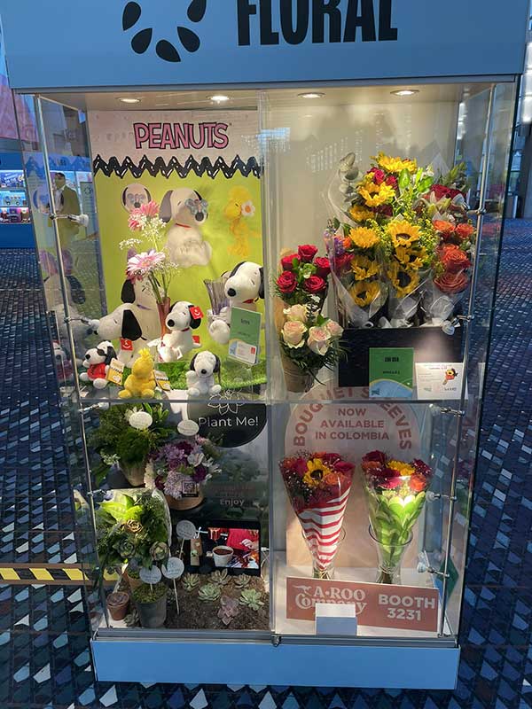 Display case with Peanuts plush toys and diverse floral arrangements.