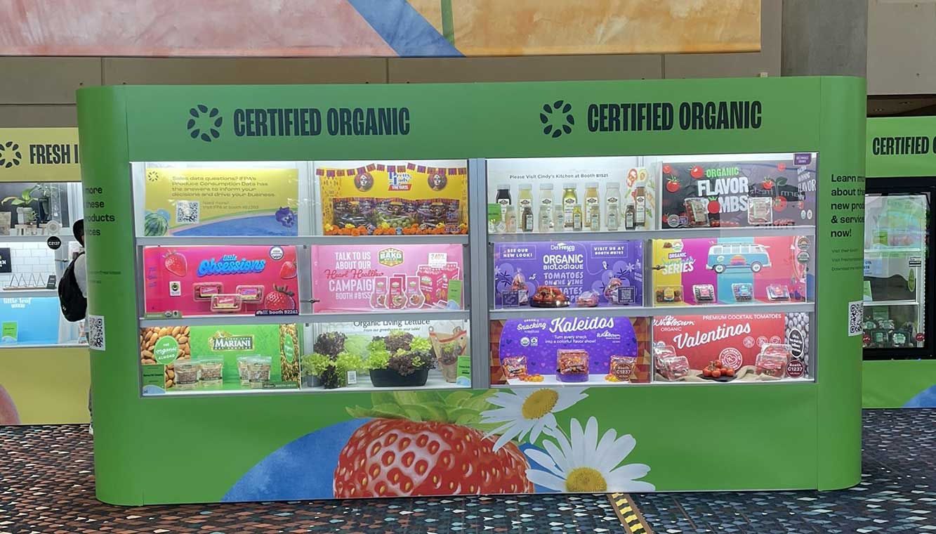 Green display stand titled "CERTIFIED ORGANIC" showcasing various organic products with colorful packaging.