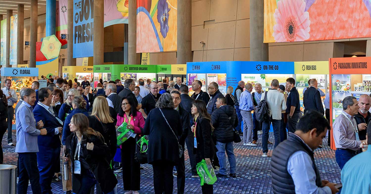 Crowded trade show with booths for floral, organic, and packaging innovations.