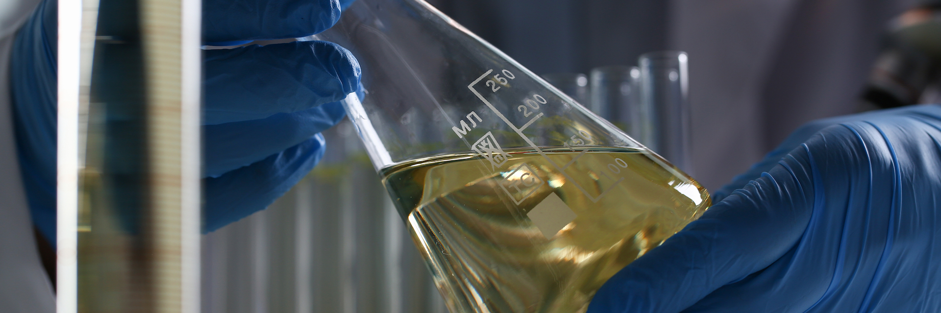 Male hand hold yellow liquid in test tube.