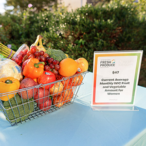 A basket of fresh produce next to a sign on a blue table.